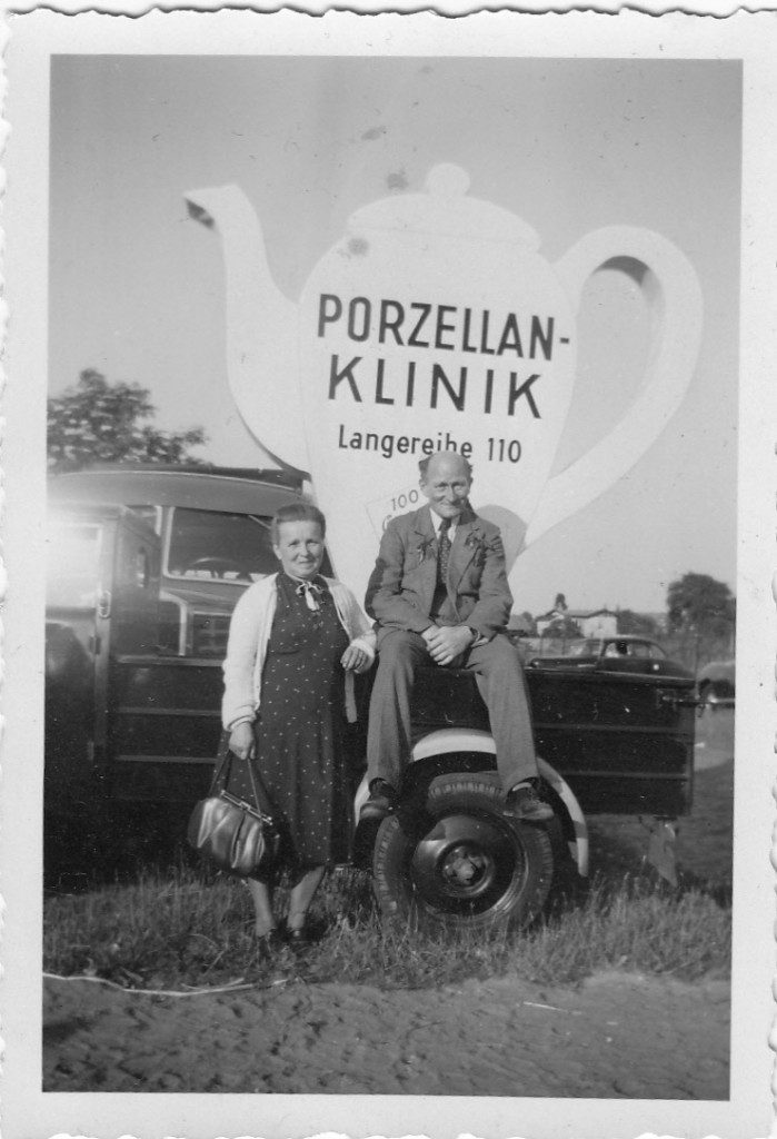 Das Kannenmobil der Porzellan-Klinik: ein Lieferwagen mit großer Kanne auf dem Dach, davor zwei Männer