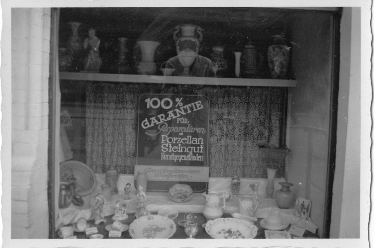 Historisches Schaufenster der Porzellan-Klinik mit dem Schild „100 % Garantie für Reparaturen“