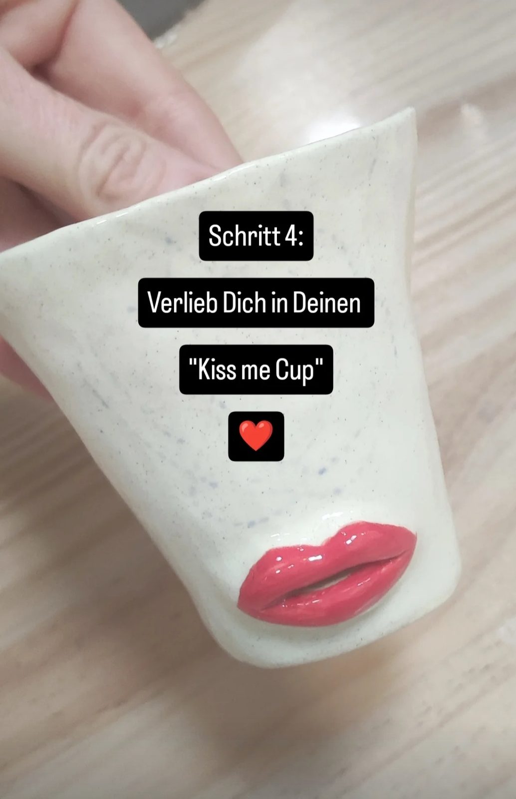 Fertiger Kiss-me-Cup mit rotem Kussmund in der Hand
