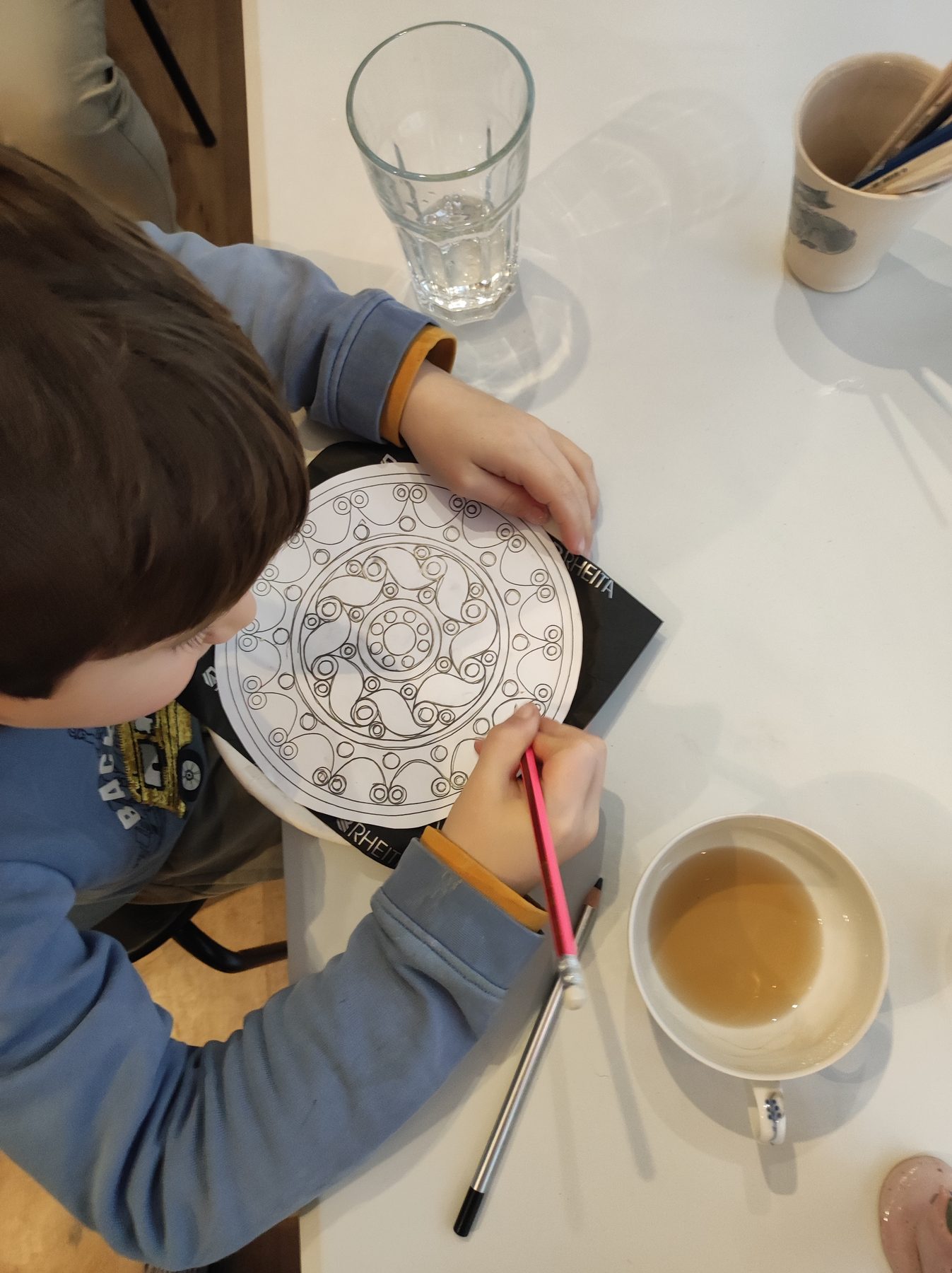 Kind bemalt konzentriert eine Keramikschale am Tisch im Kreativstudio