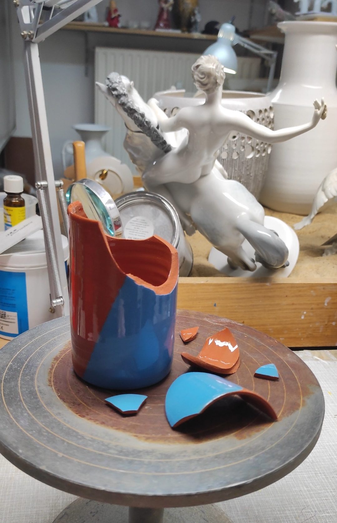 Scherben einer blauen Vase auf der Drehscheibe in der Werkstatt, bereit zum Zusammensetzen